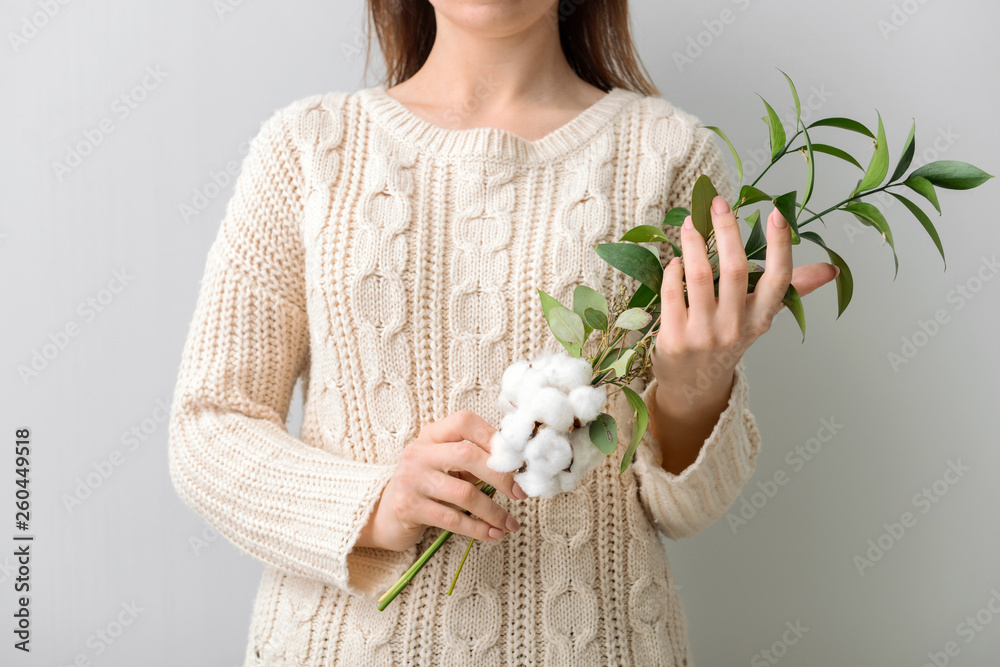 拿着浅色背景棉花花的花卉作品的女人