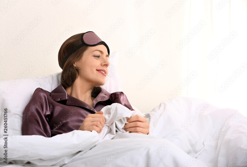 Young woman with sleep mask in bed