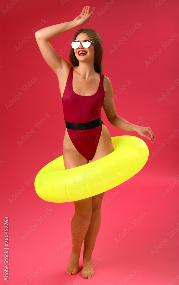 Beautiful young woman with inflatable ring on color background