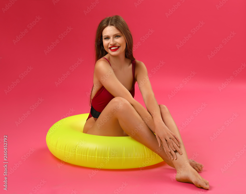 Beautiful young woman with inflatable ring on color background