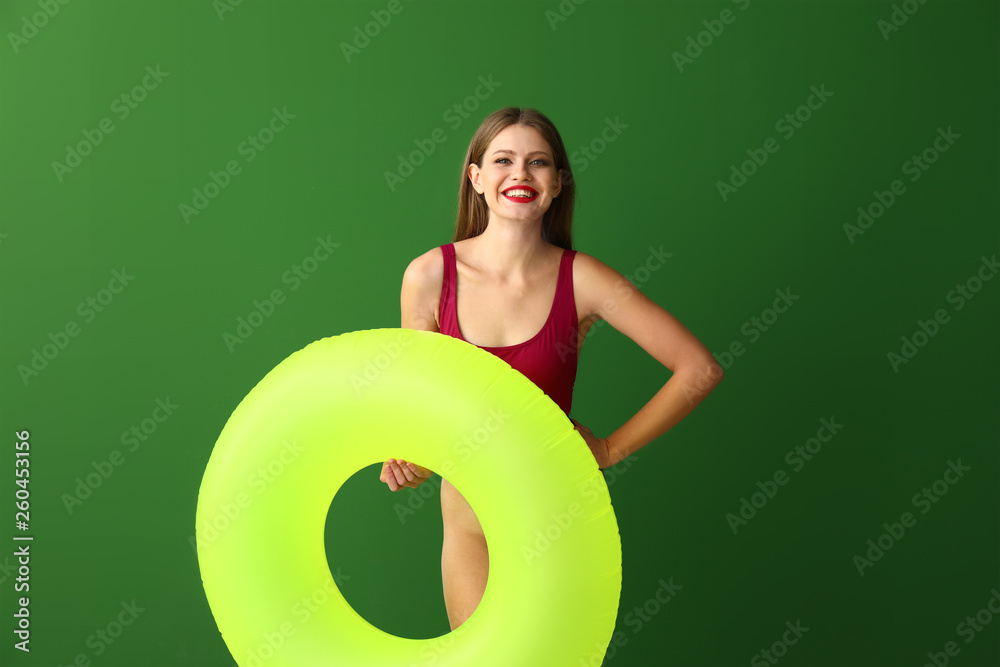 Beautiful young woman with inflatable ring on color background