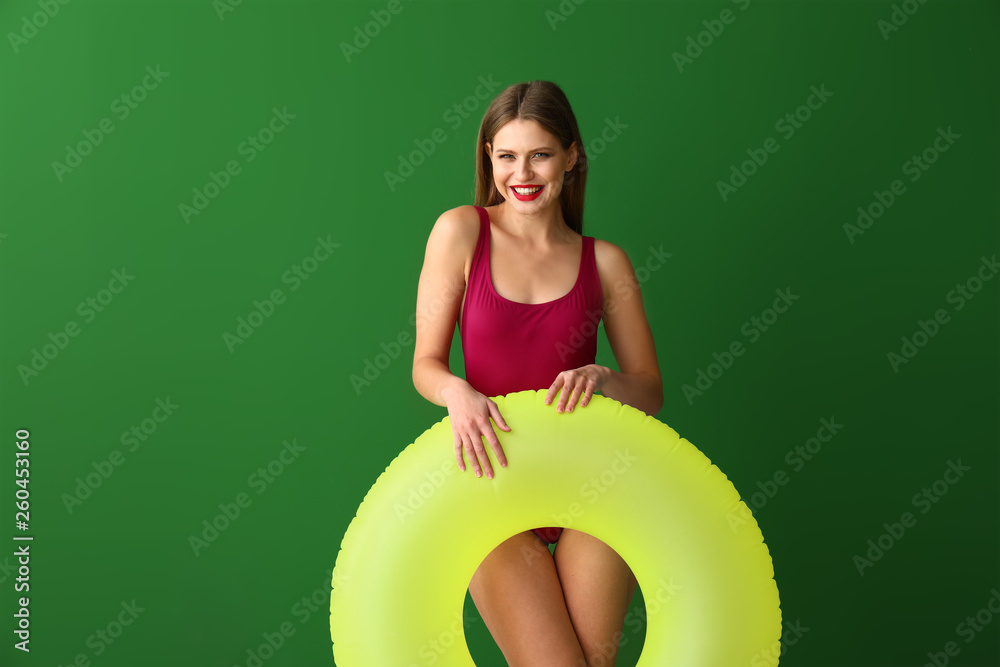 Beautiful young woman with inflatable ring on color background