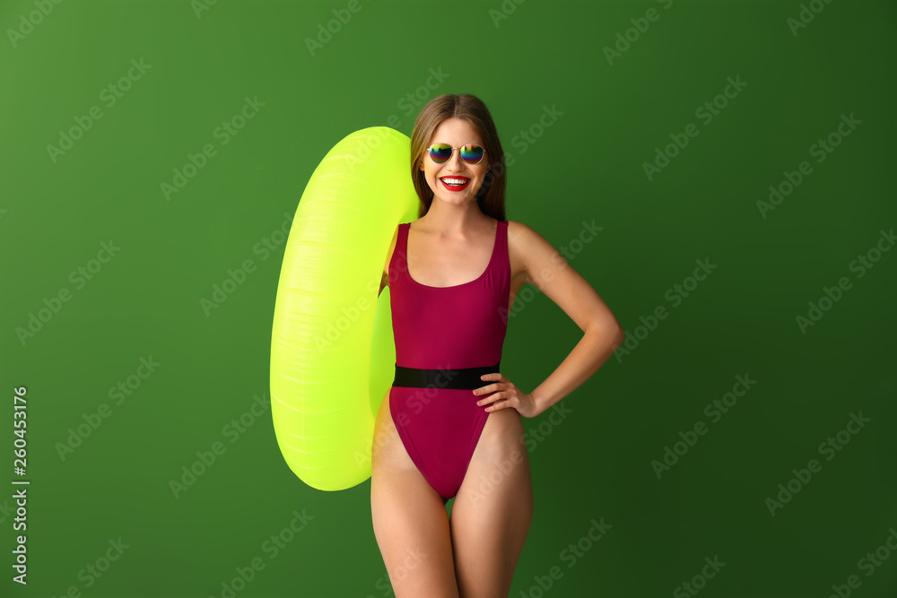 Beautiful young woman with inflatable ring on color background