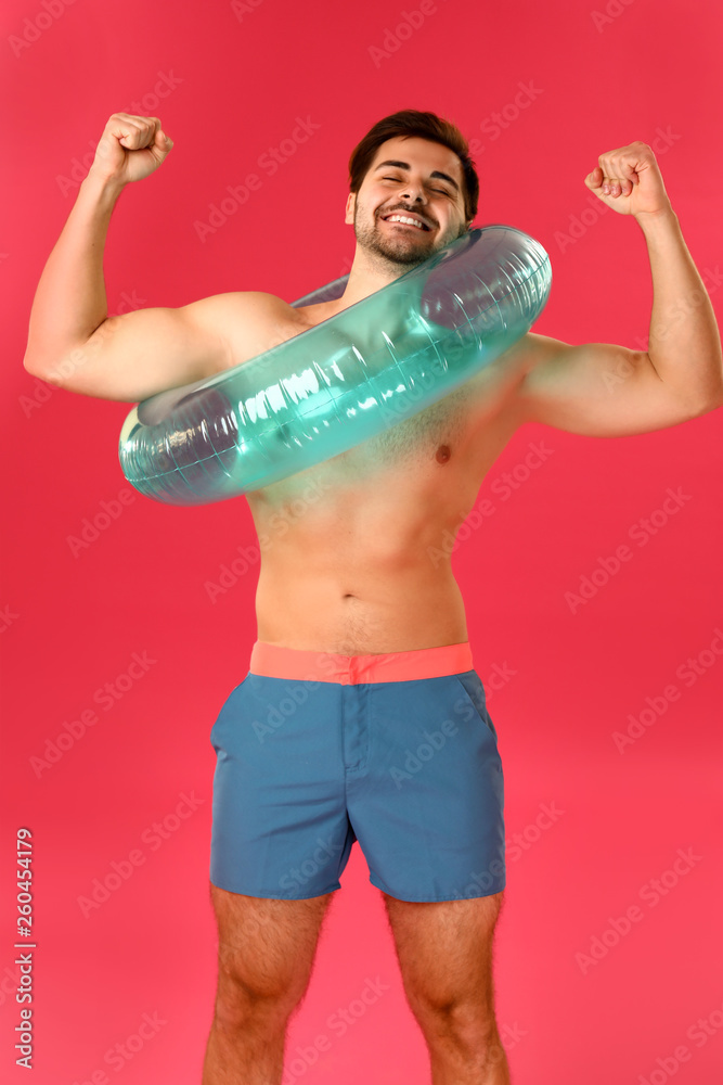 Handsome man with inflatable ring on color background