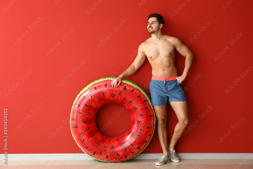 Handsome man with inflatable ring near color wall