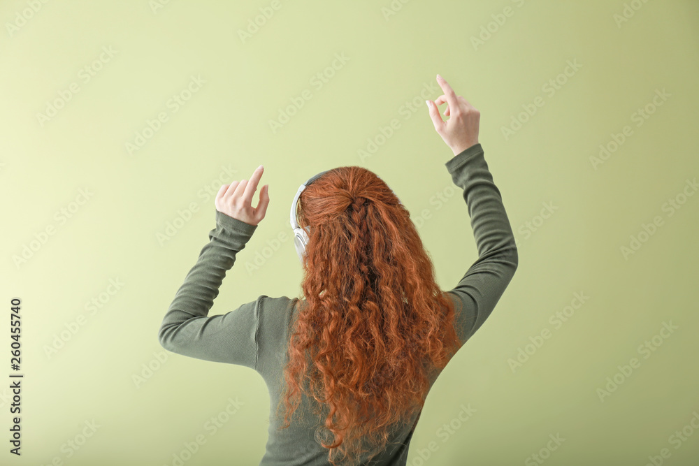 Young woman with headphones listening to music on color background