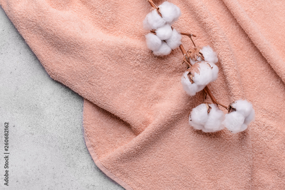 Cotton flowers with soft towel on grey background