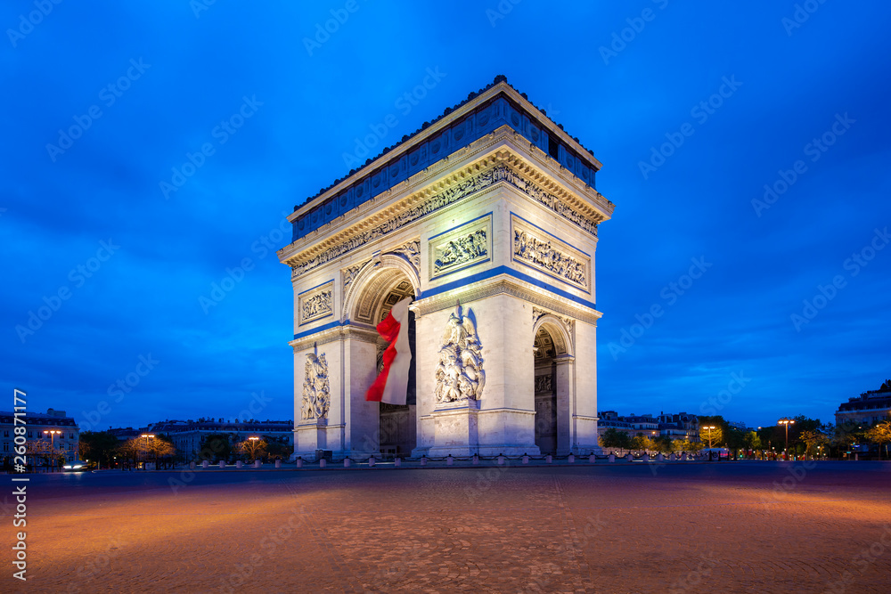 Paris street at night with the Arc de Triomphe in Paris, France.