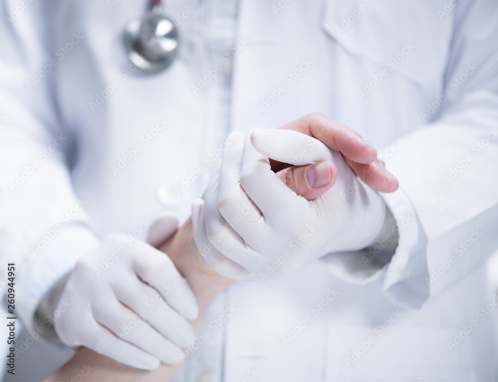 Medical doctor wearing latex gloves holding patient’s hand to give support in hospital setting