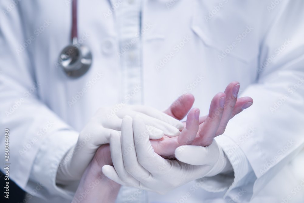 Medical doctor wearing latex gloves holding patient’s hand to give support in hospital setting