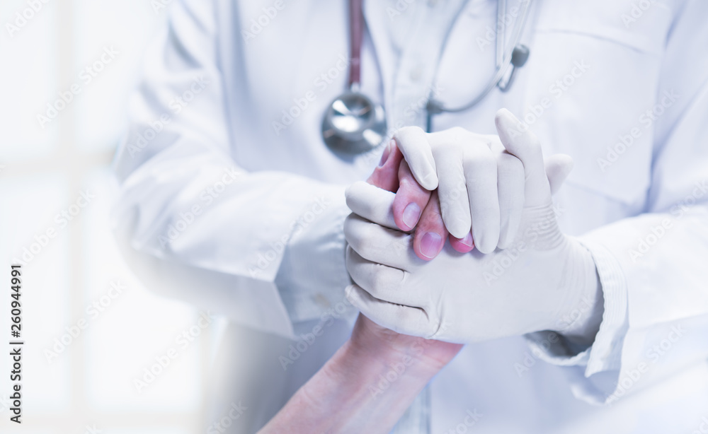 Medical doctor wearing latex gloves holding patient’s hand to give support in hospital setting