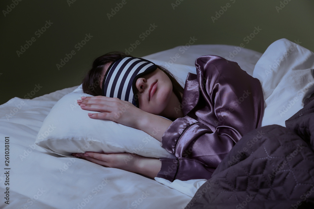 Young woman with sleep mask in bed at night