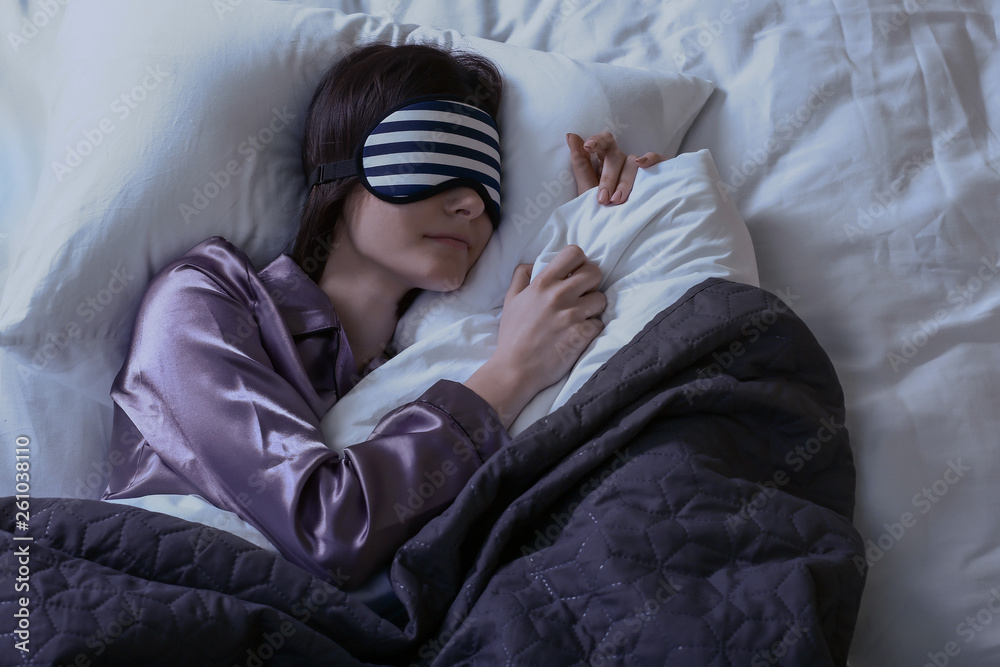 Young woman with sleep mask in bed at night