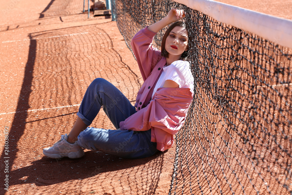 Fashionable young woman on tennis court outdoors