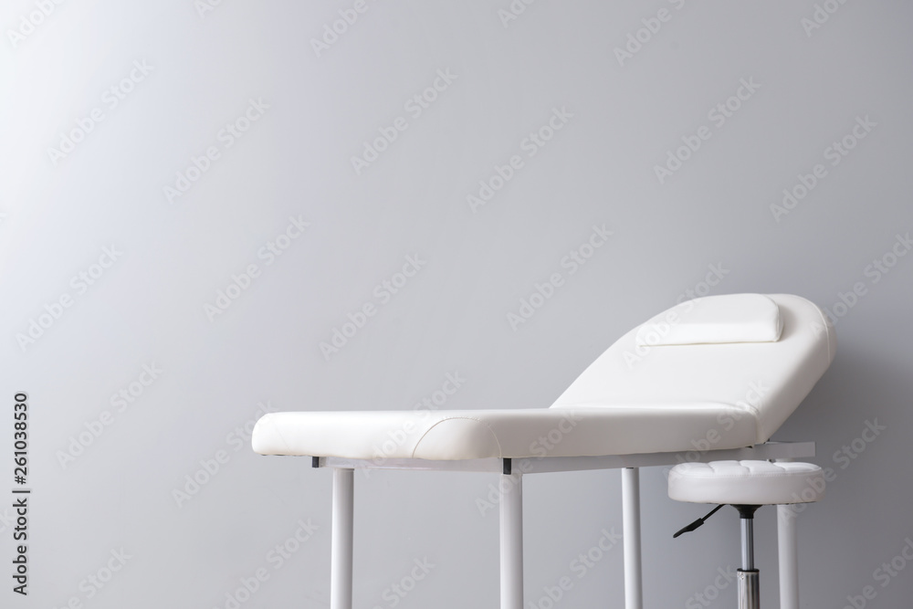 Treatment couch with stool on grey background