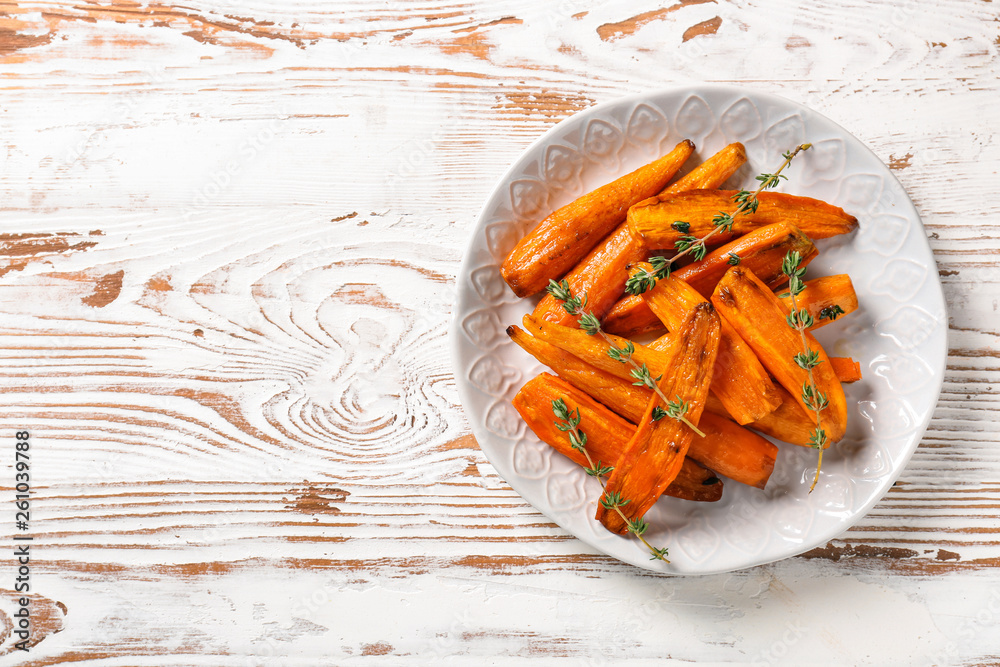 Plate with tasty cooked carrot on wooden table