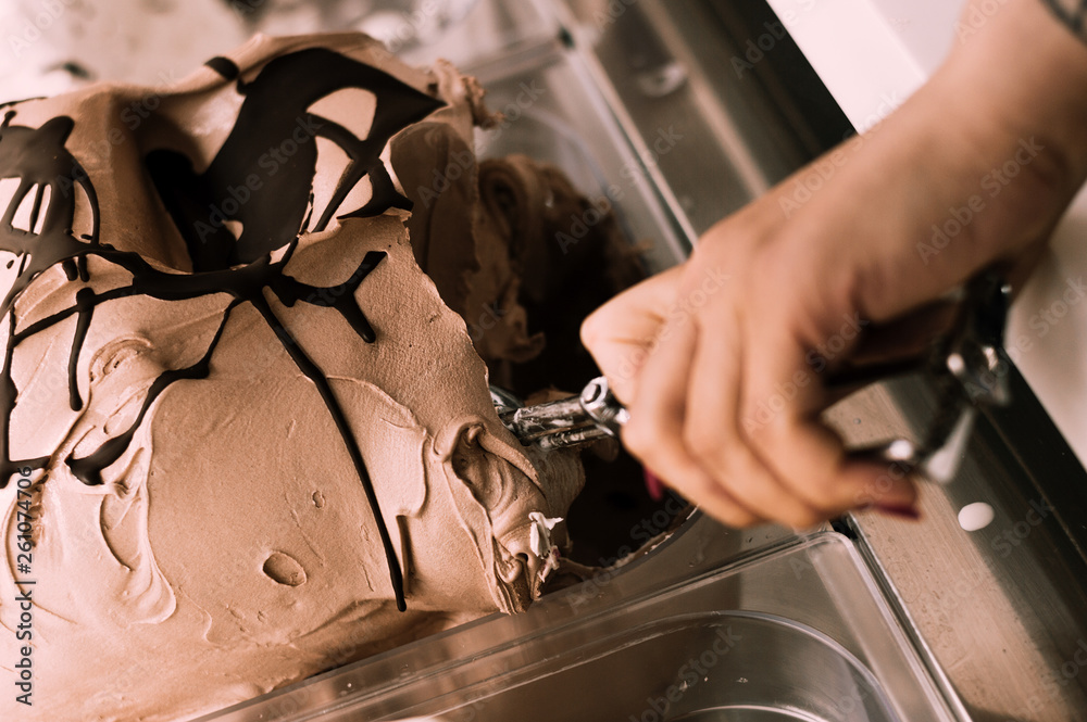 Female hand with scoop taking ice cream. Close-up. Top view.