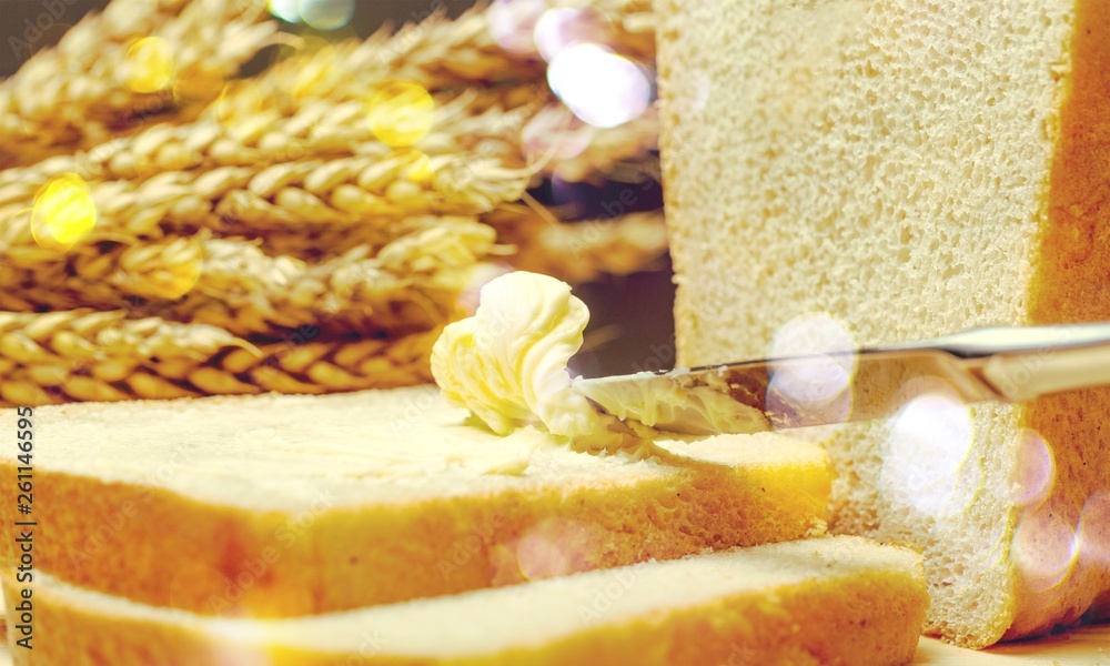 Slices of bread with butter on wheat background