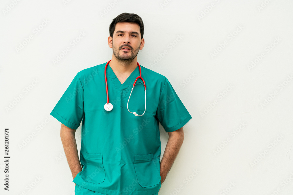 Portrait of young male medical staff in green uniform with stethoscope on white background. Medical 