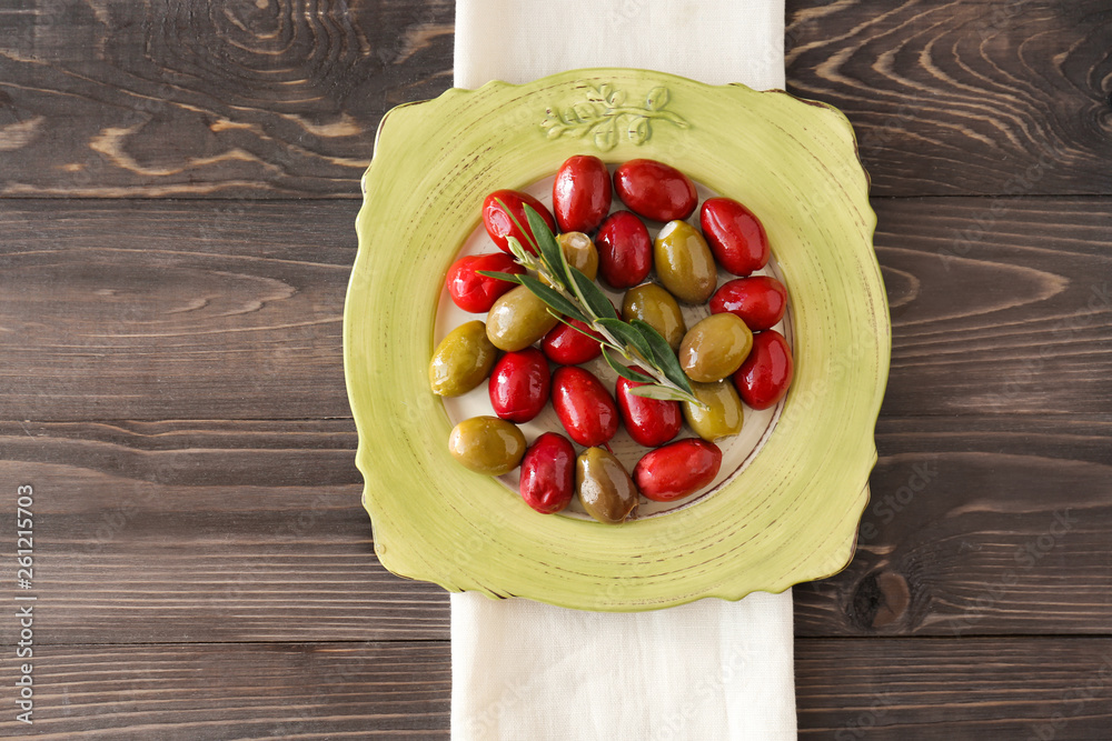 Plate with tasty olives on wooden table