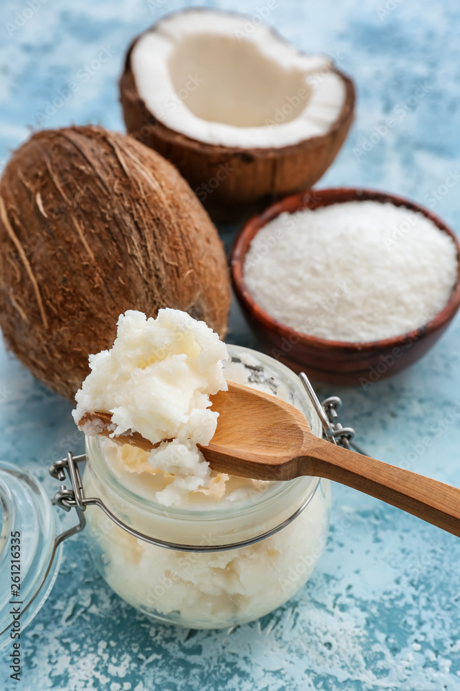 Jar with coconut oil on color background