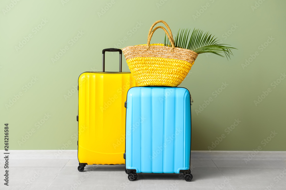 Packed suitcases and beach bag near color wall