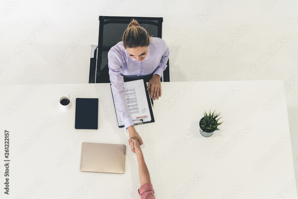 两位年轻的商界女性在办公桌上会面，讨论求职申请和商业协议。Recr