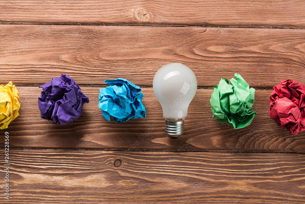 Ideological concept with wastepaper light bulb on wooden table