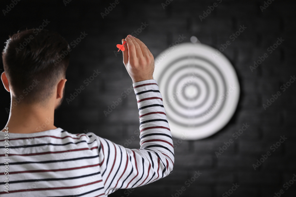 Young man playing darts indoors