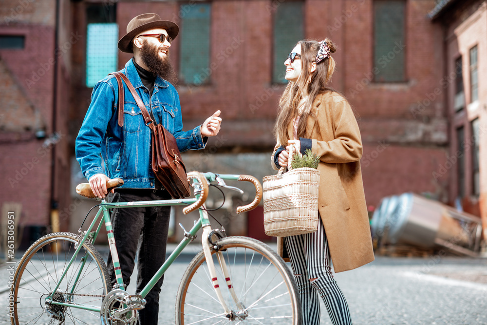 Stylish young man and woman having a conversation standing together with retro bicycle outdoors on t