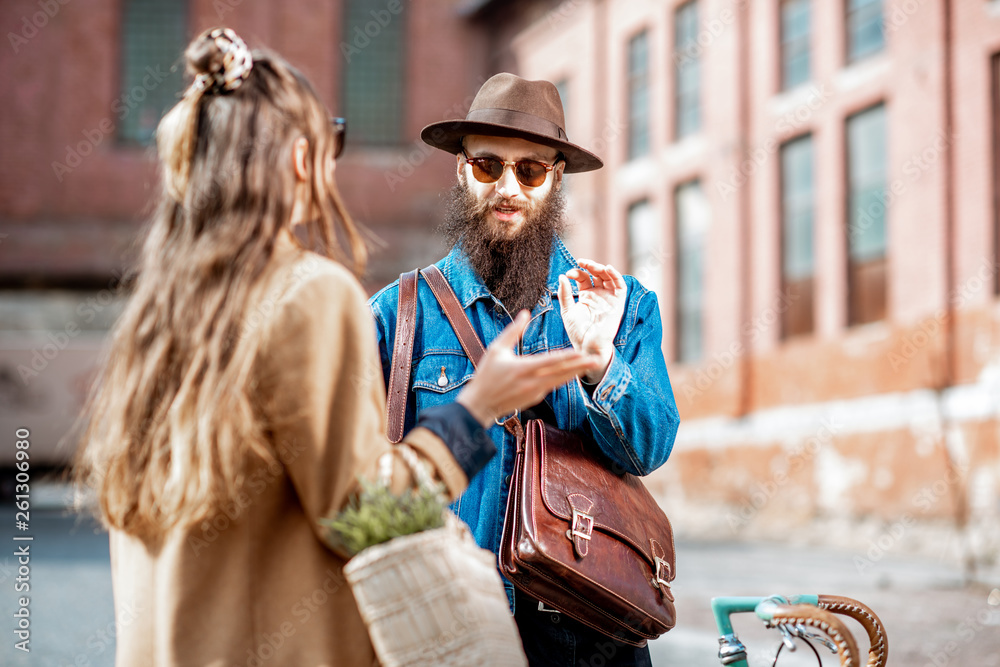 Stylish young man and woman having a conversation standing together with retro bicycle outdoors on t