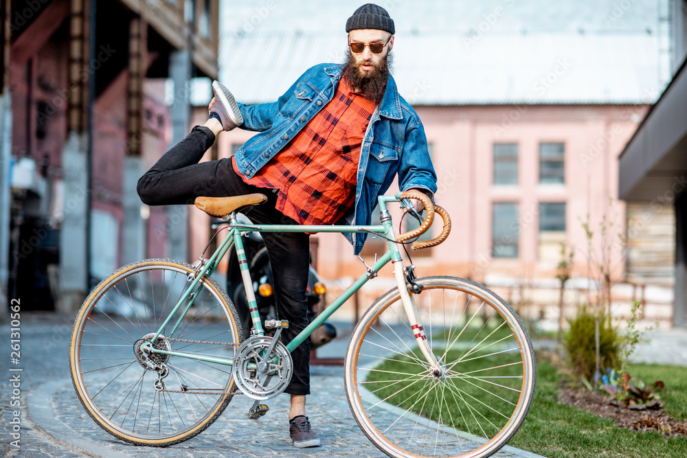 Portrait of a bearded man as a crazy hipster having fun with retro bicycle outdoors on the industria