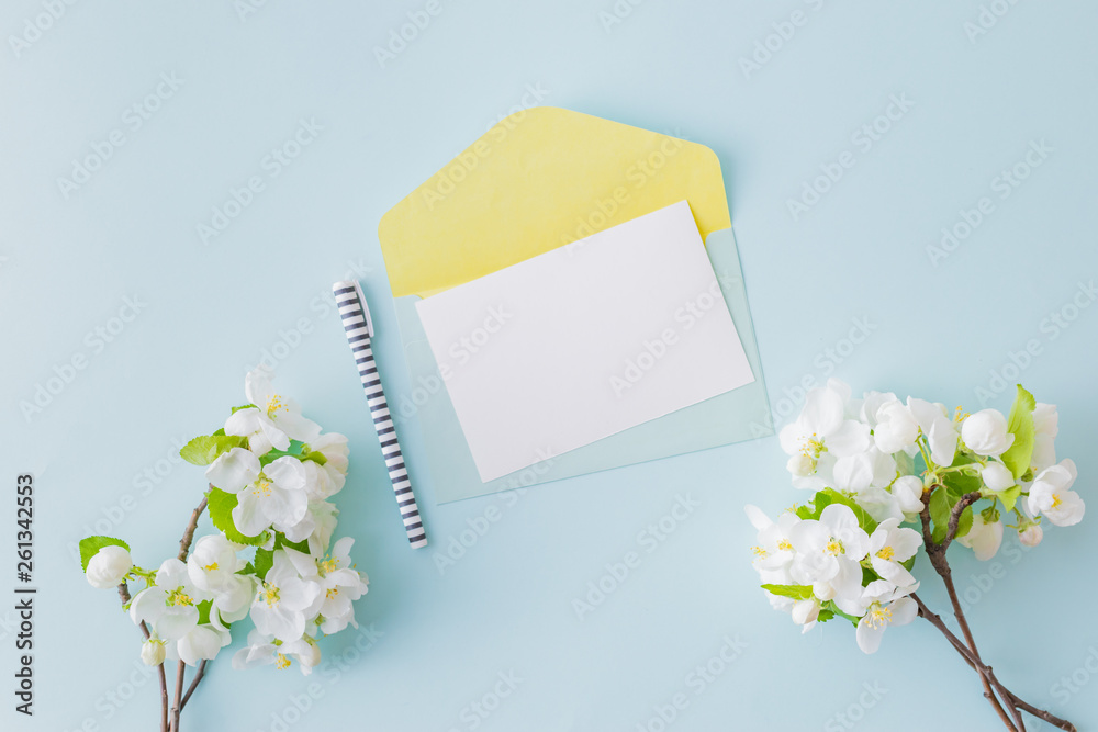 Mockup white wedding invitation and envelope with white flowers on a blue background