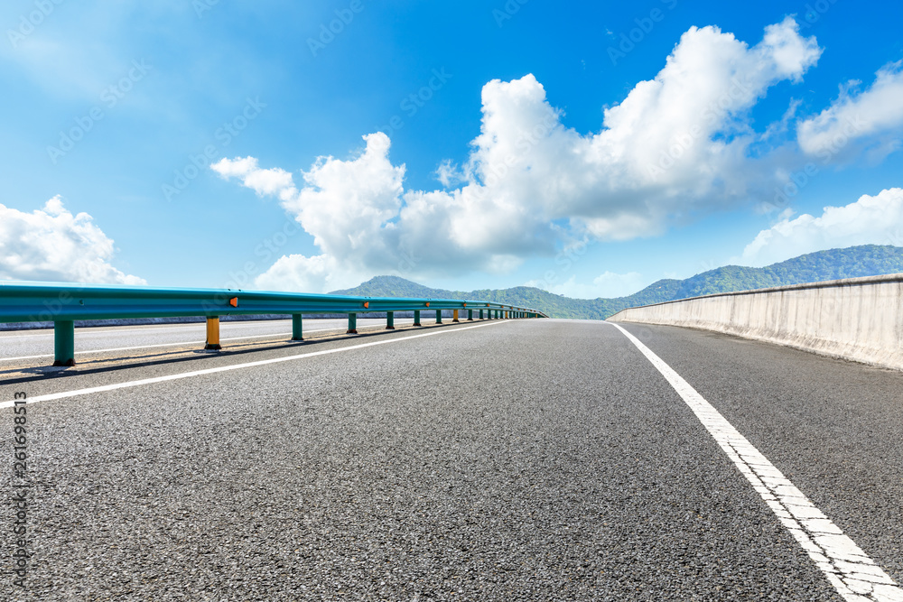 Empty asphalt road and mountains with blue sky on a sunny day