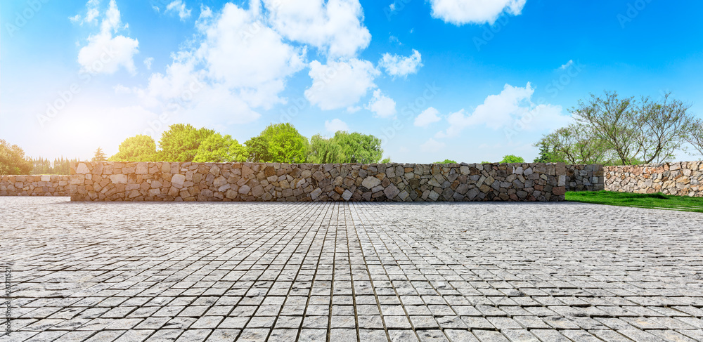 Rough square stone floor and green woods with sky background