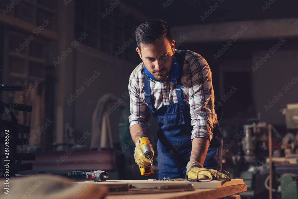 Carpenter drills a hole with an electrical drill