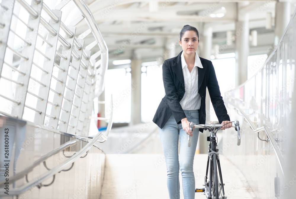 Young business woman with bike walking along sidewalk outdoors in urban city, Pushing Bike City Conc