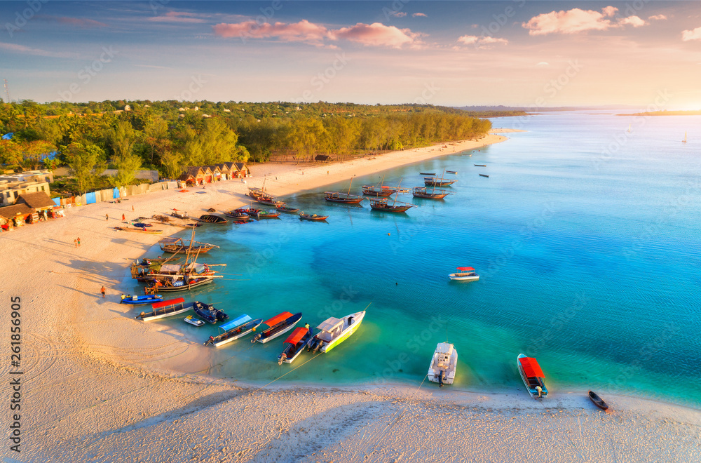 Aerial view of the fishing boats on tropical sea coast with sandy beach at sunset. Summer holiday. I