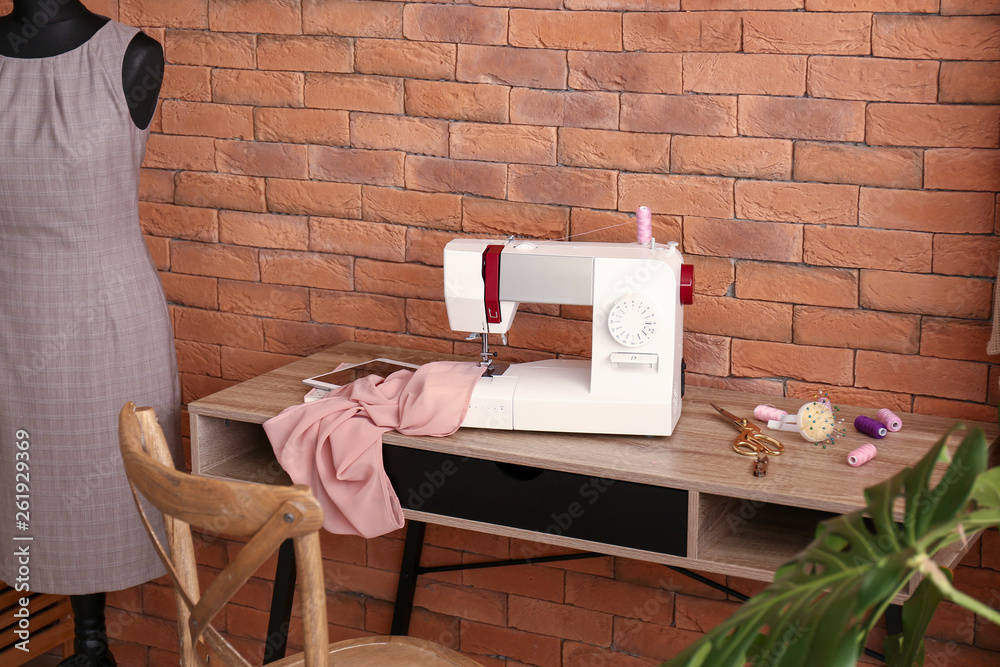 Stylish workplace of tailor with sewing machine in workshop