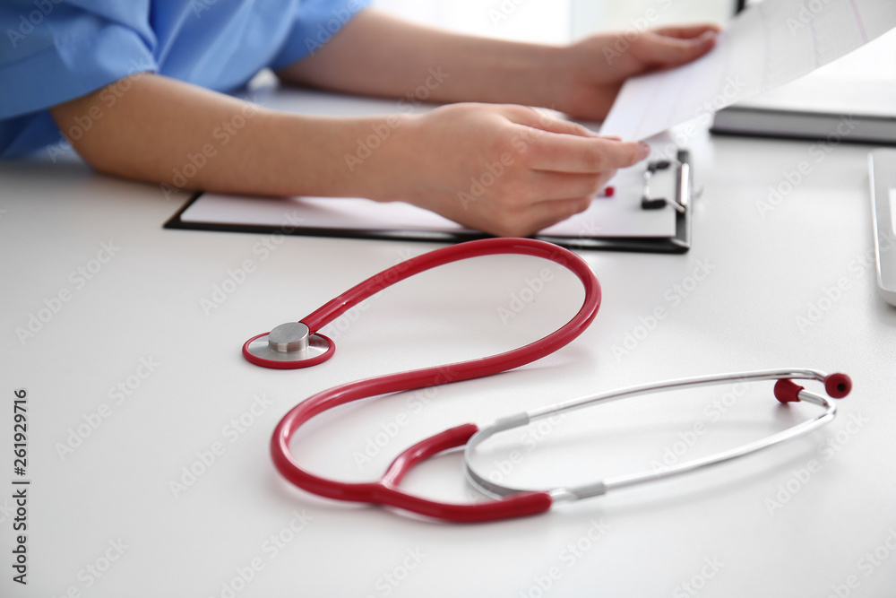 Stethoscope and doctor working at table