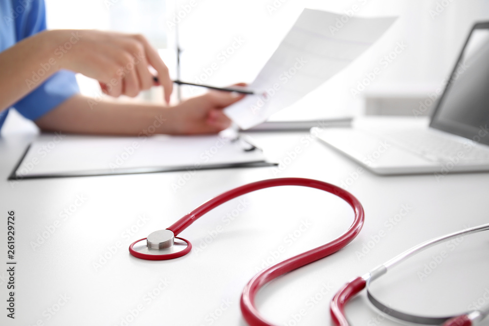 Stethoscope and doctor working at table