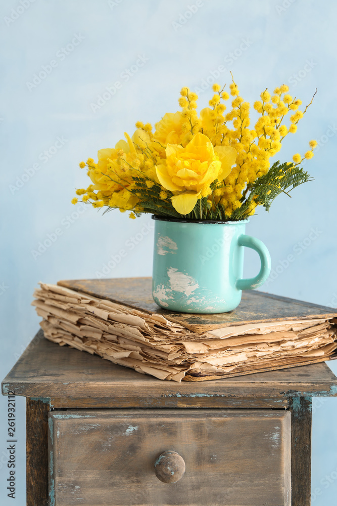 杯子上有美丽的黄色花朵，桌子上有彩色背景的旧书