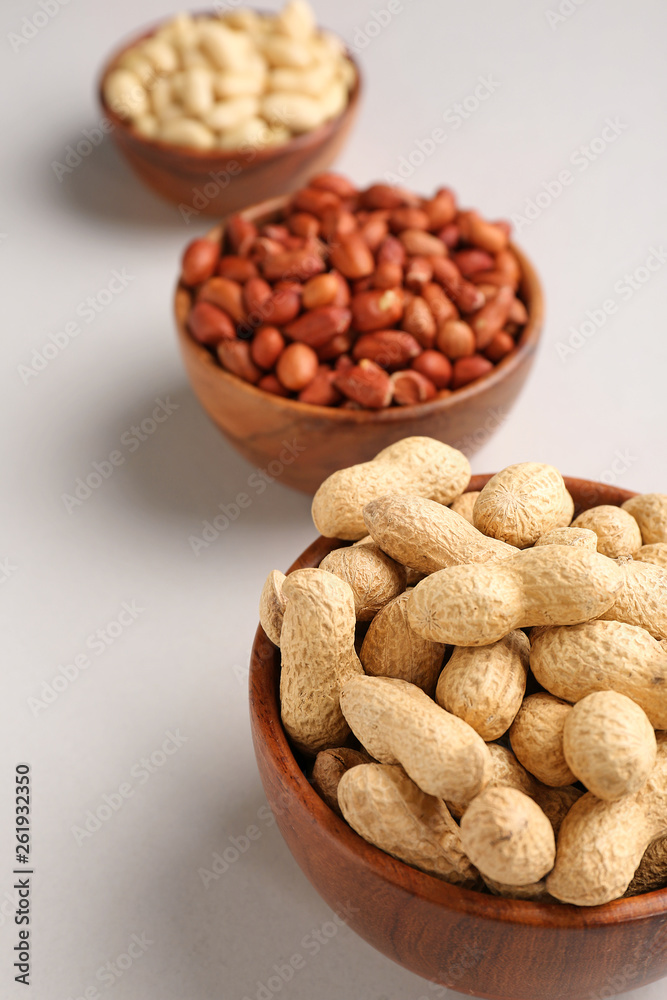 Bowls with tasty peanuts on light background