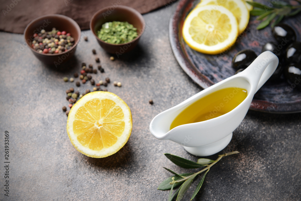 Gravy boat with tasty olive oil, lemon and spices on grey table