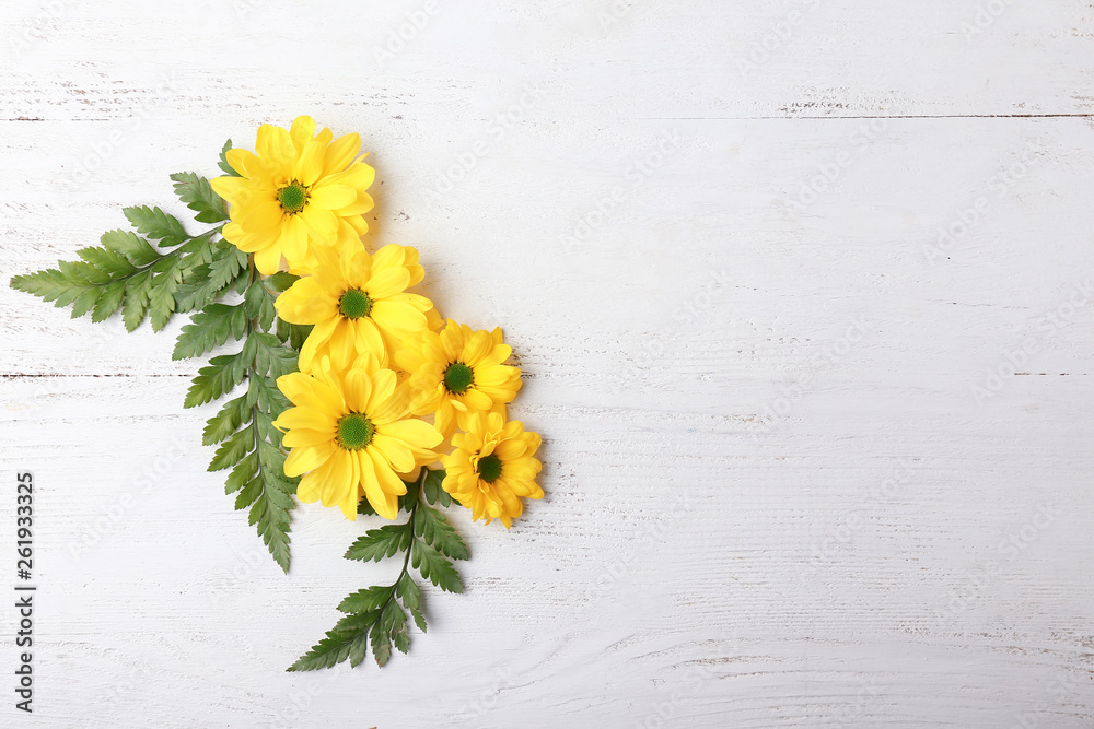 Beautiful flowers with leaves on white wooden background