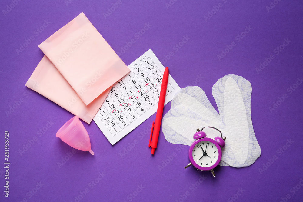 Menstrual calendar with feminine products and alarm clock on color background