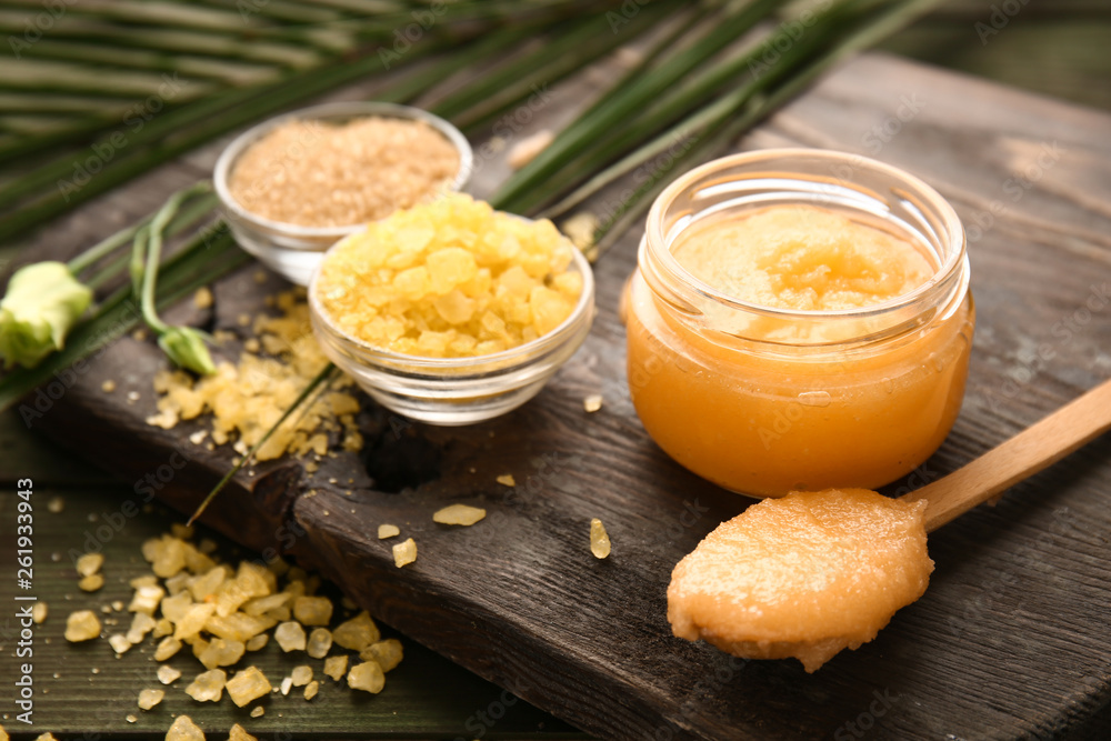 Jar with sugar scrub on wooden board