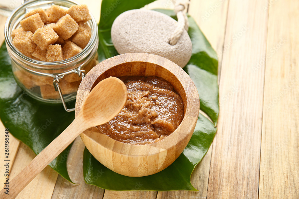 Bowl with sugar scrub on wooden table