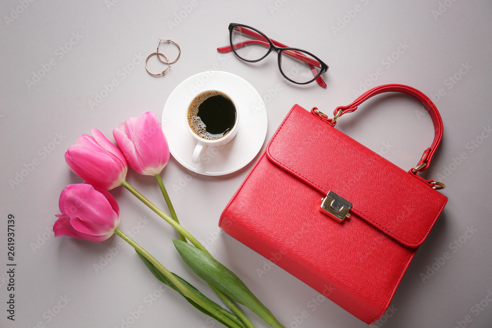 Composition with beautiful tulips, female accessories and cup of coffee on grey background