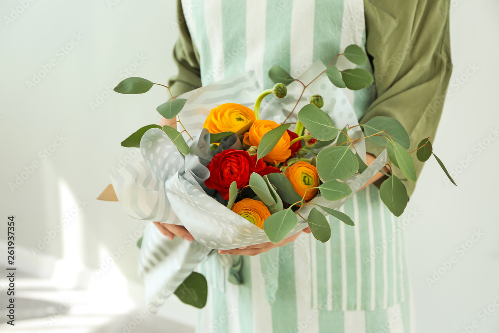 Florist holding beautiful bouquet on light background